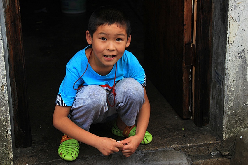 p17 临街的门口,一个小男孩蹲着身子在雨中玩耍