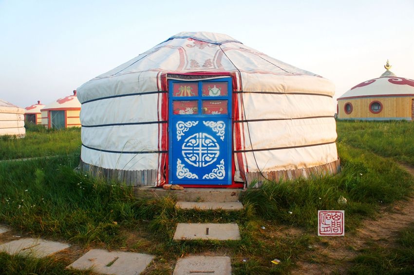 蒙古包三三两两坐落在草原上,有的还装饰着由红,蓝,黄等颜色布料做成
